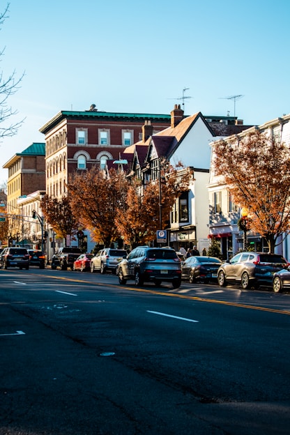 a city street lined with parked cars next to tall buildings