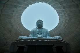 a buddha statue sitting in front of a round window