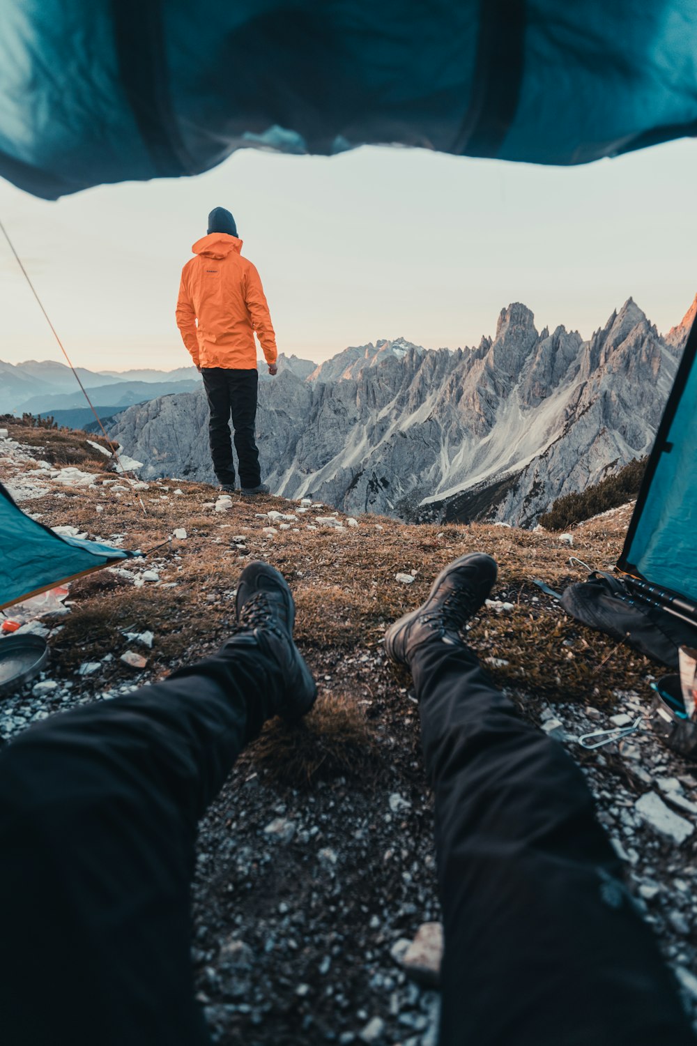 a man standing on top of a mountain next to a tent