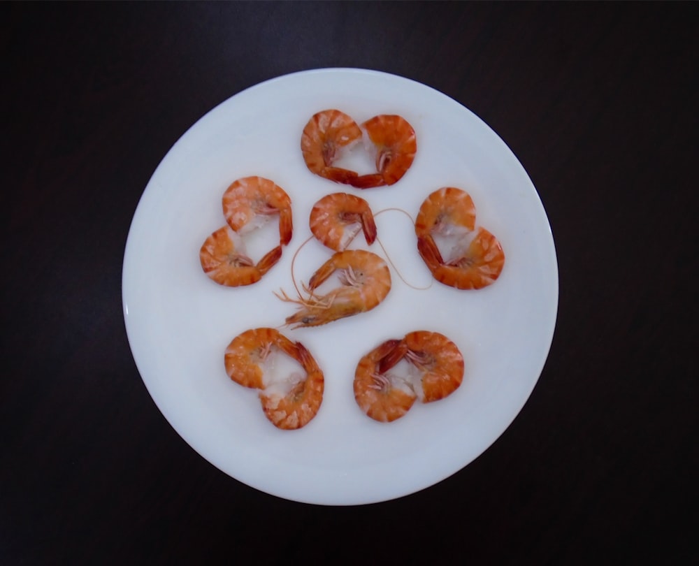 a white plate topped with shrimp on top of a table