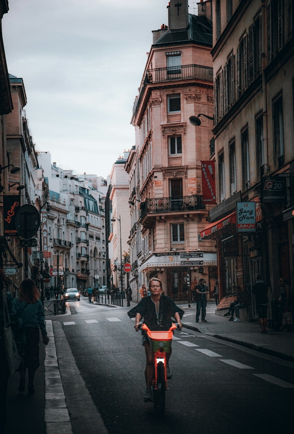 a man riding a motorcycle down a street next to tall buildings