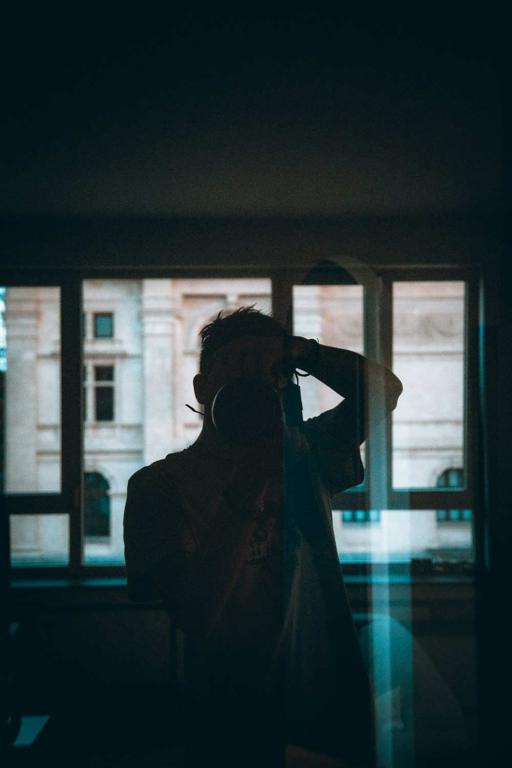 una persona in piedi davanti a una finestra in una stanza buia