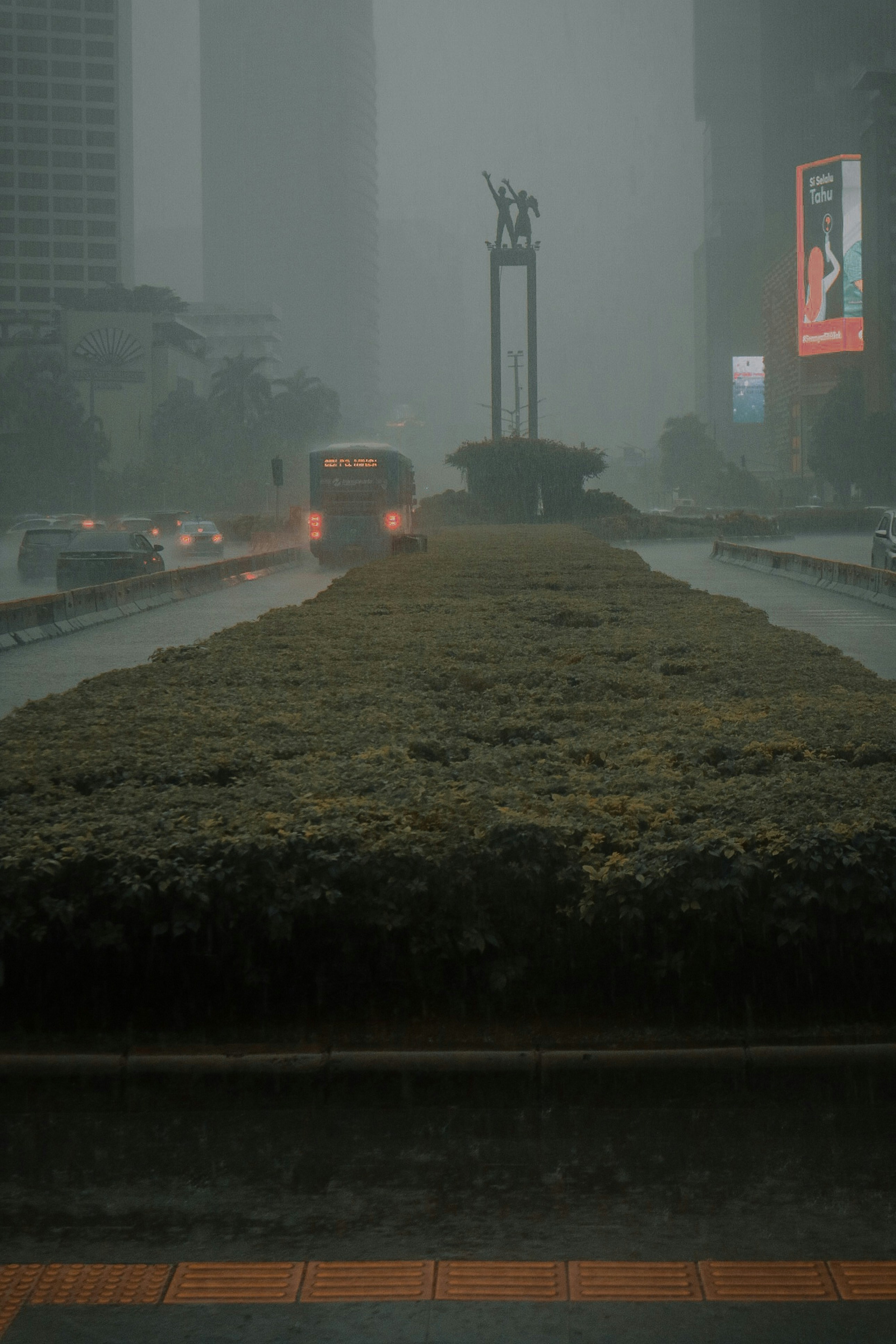 a foggy city street with cars driving on it
