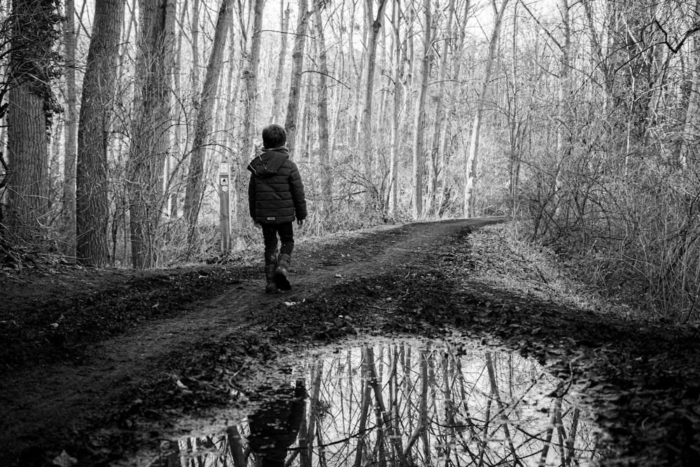 a person walking down a dirt road in the woods