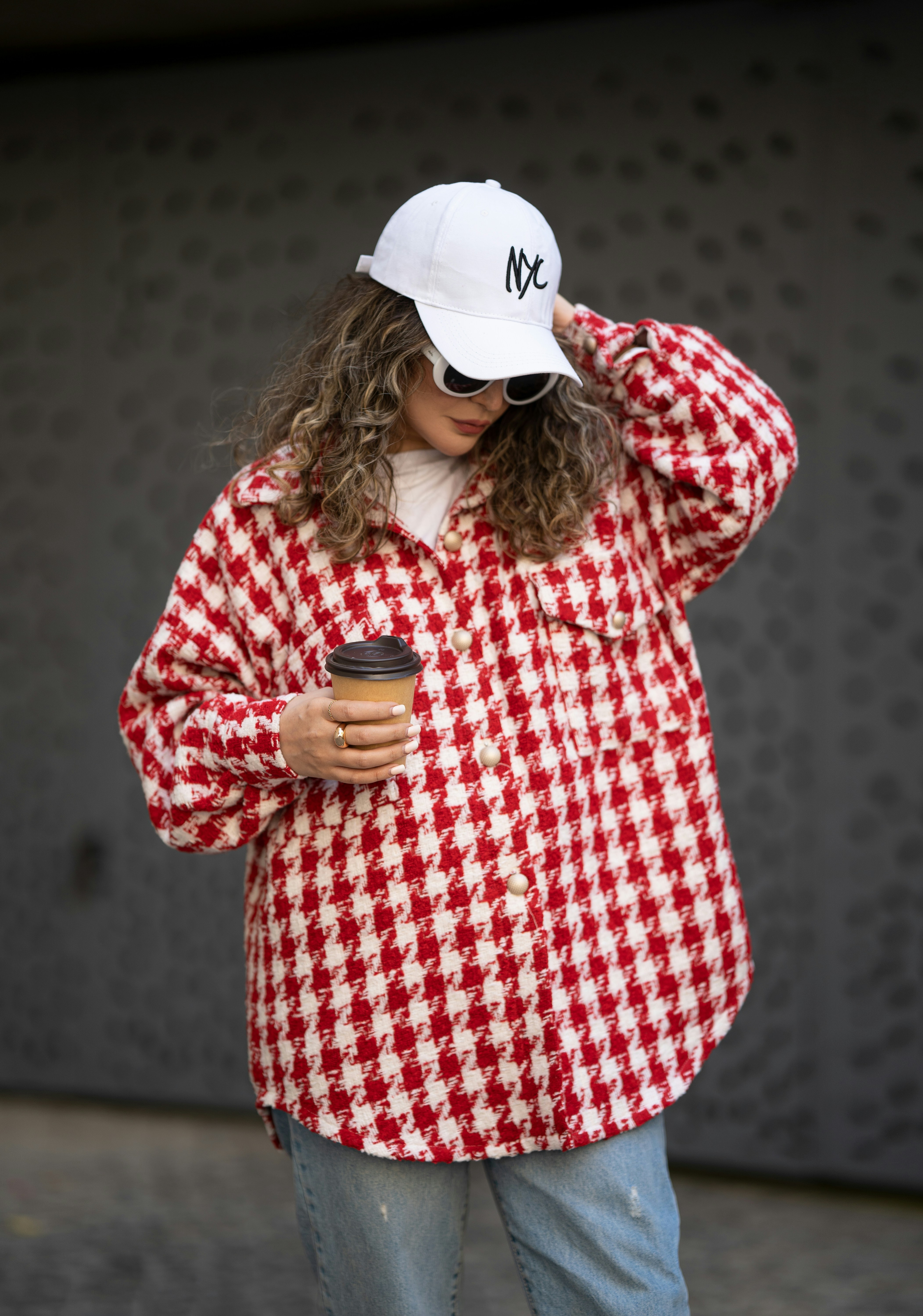 A woman in a red and white checkered jacket holding a cup of coffee ...