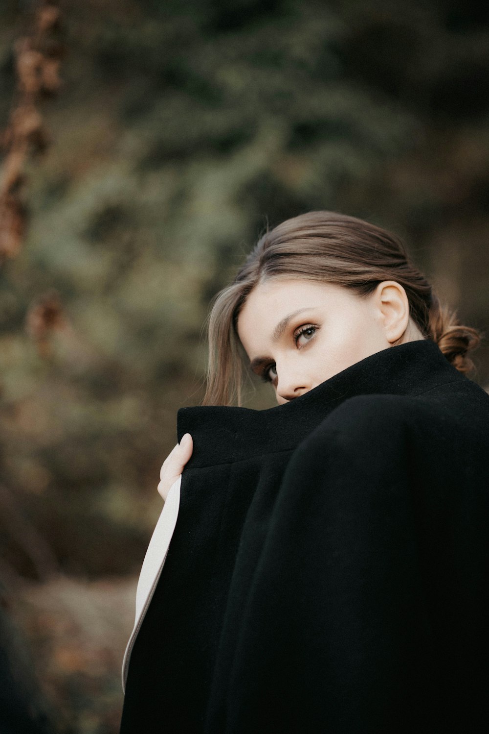 a woman in a black coat is posing for a picture