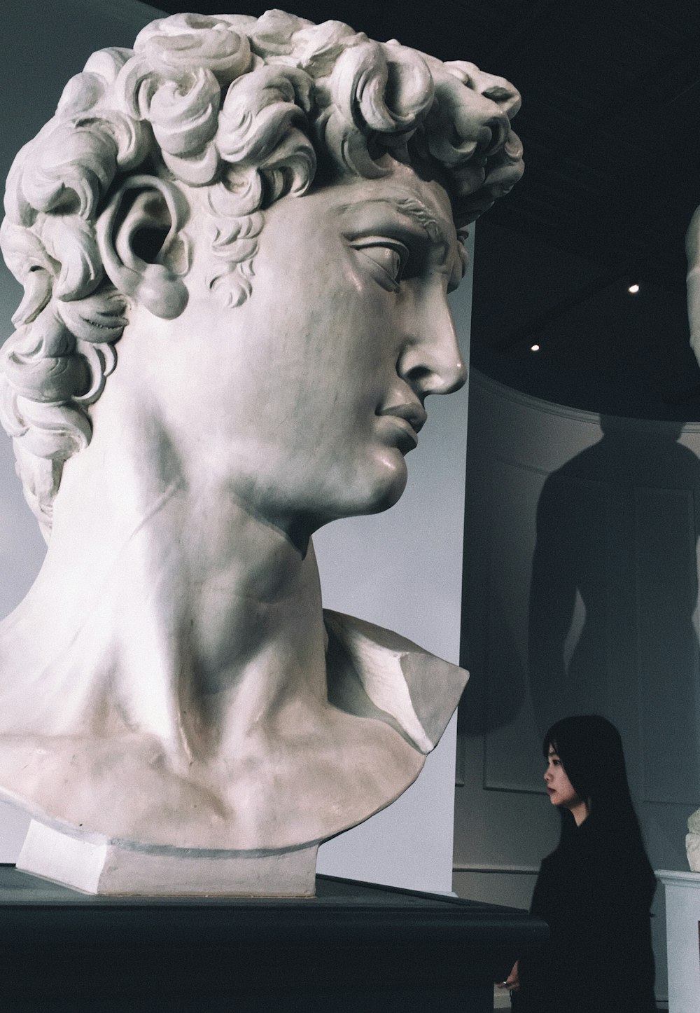 a woman standing in front of a bust of a man