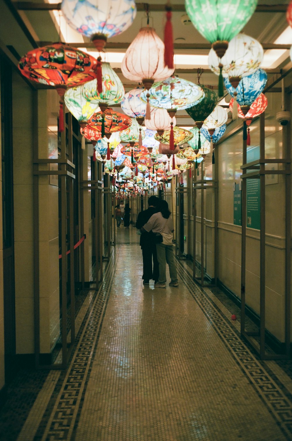 a couple of people walking down a long hallway