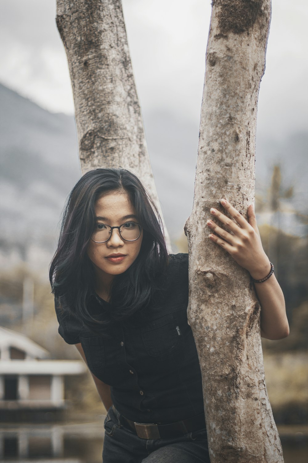 a woman wearing glasses leaning against a tree
