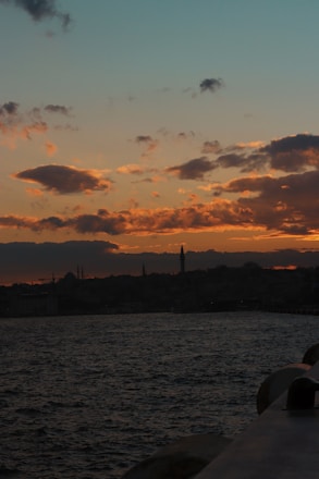 A scenic view of Istanbul's skyline at sunset with a silhouette of a traveler.