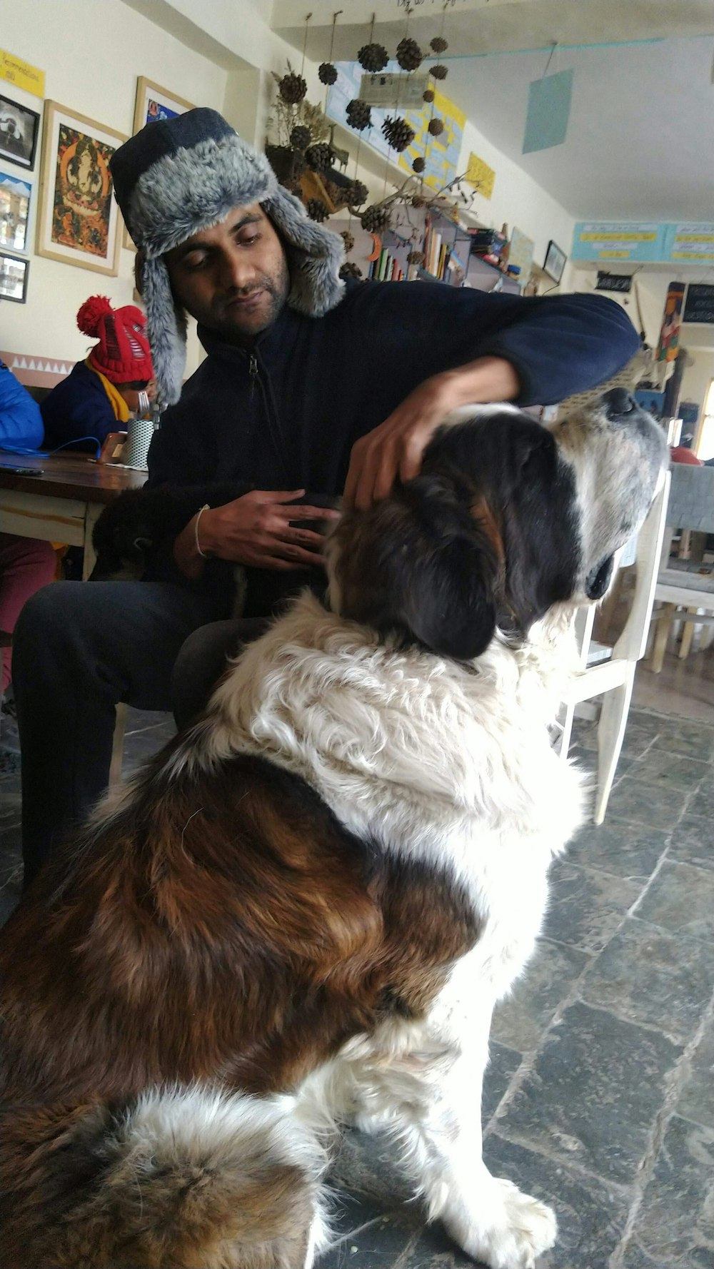 a man sitting in a chair petting a brown and white dog