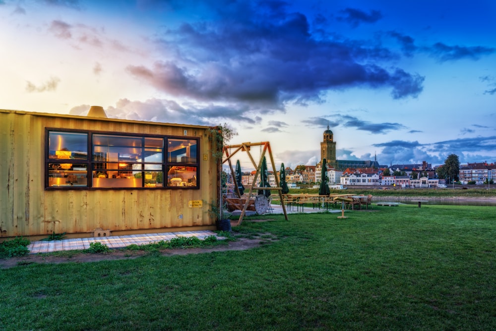 a small wooden structure with windows on a grassy field