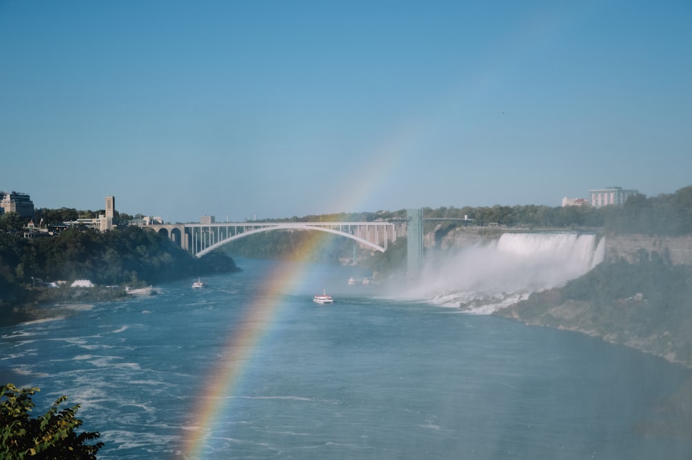 a rainbow in the sky over a river and a bridge