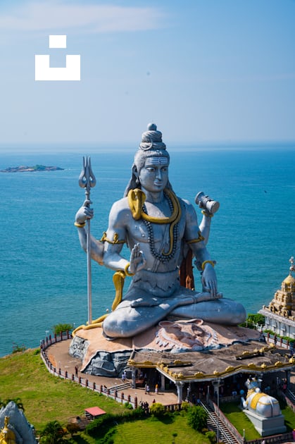 A statue of a person sitting on top of a hill photo – Free Murudeshwar ...