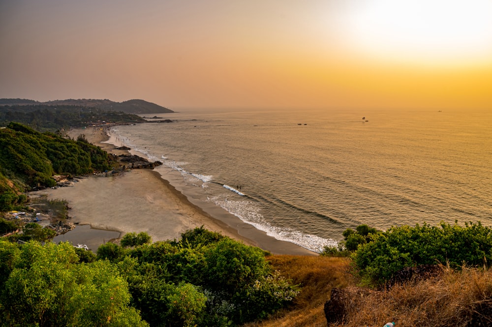 the sun is setting over the ocean and a beach