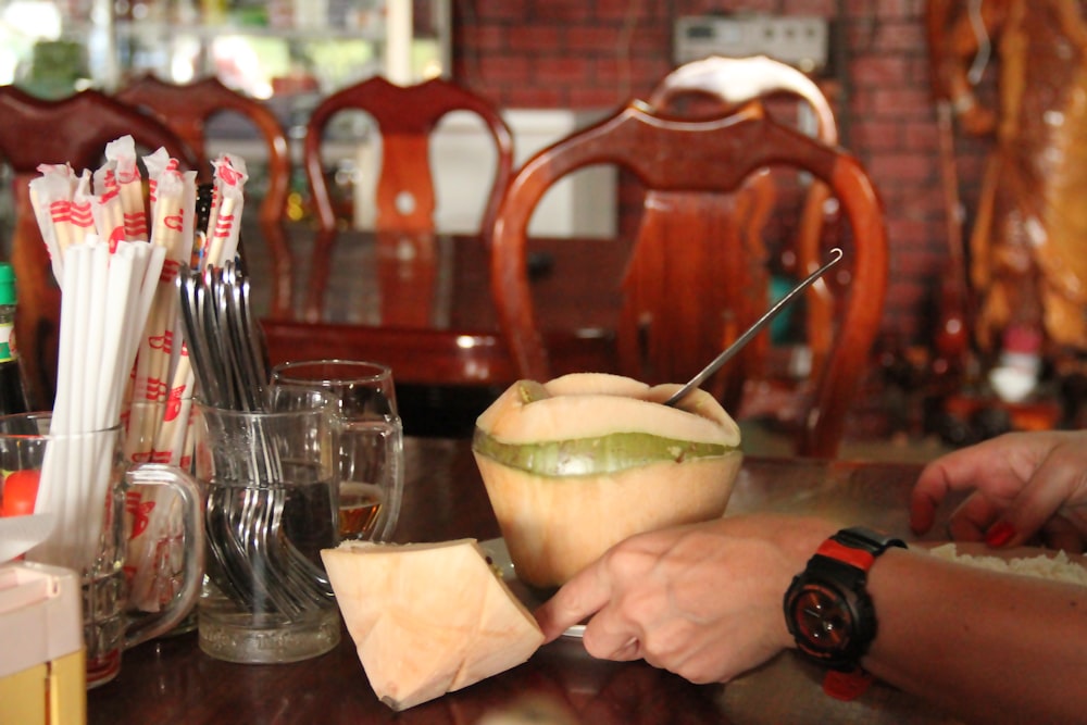 a person cutting a melon with a knife on a table