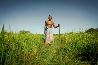 An elderly man walking confidently outdoors with a walking stick.