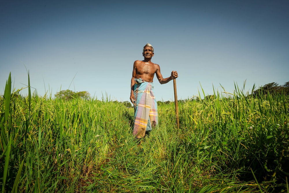 a man standing in a field holding a stick