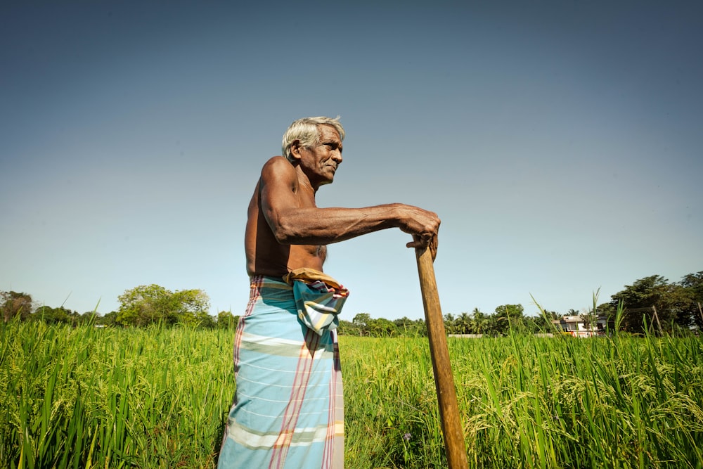 a man standing in a field holding a stick