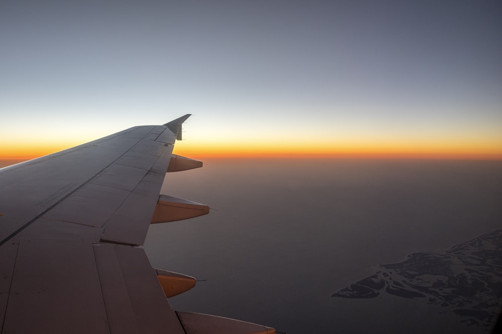 Der Flügel eines Flugzeugs, wenn die Sonne untergeht