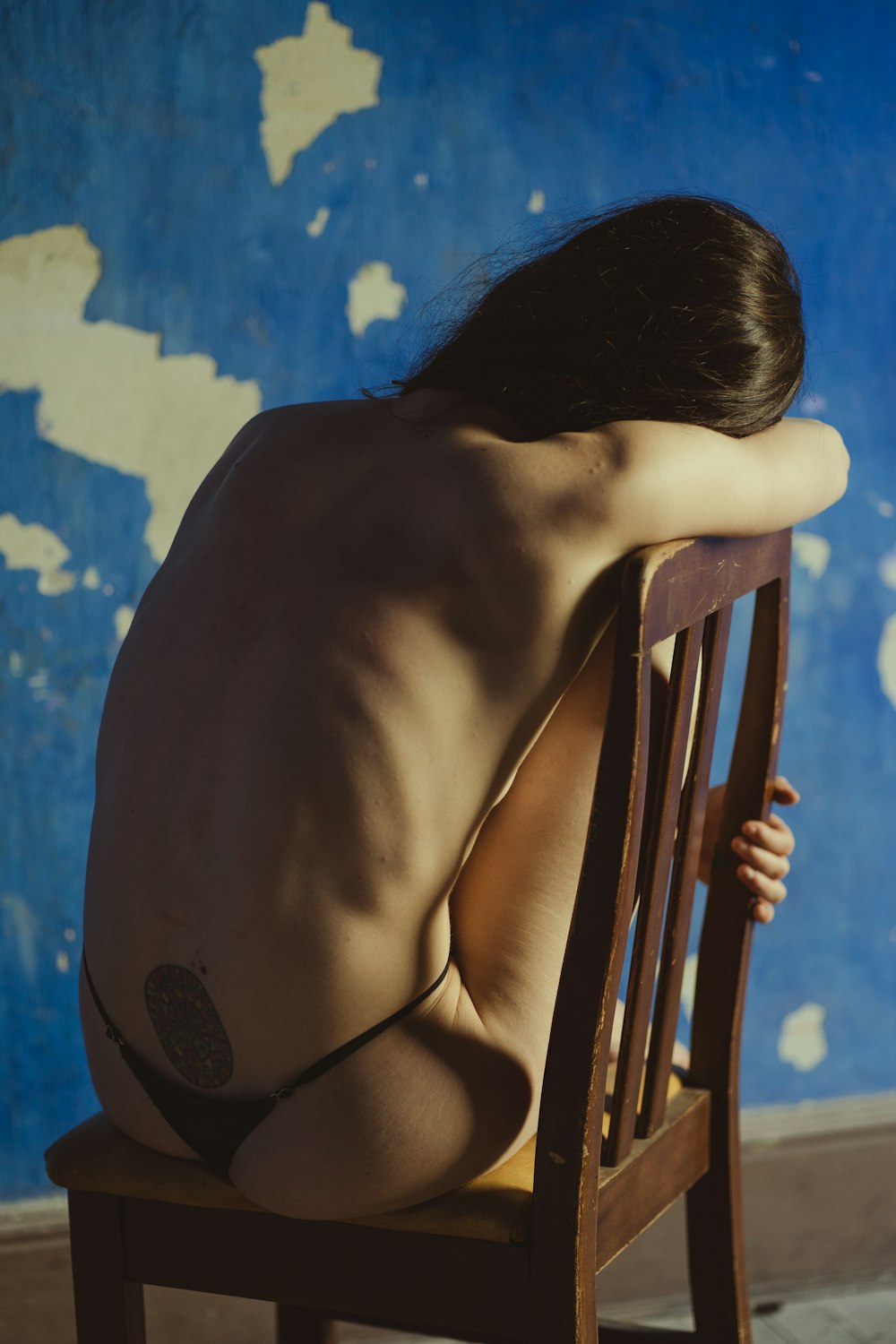 a naked man sitting in a chair in front of a blue wall