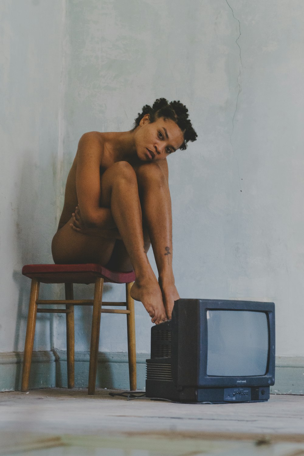 a naked man sitting on a chair next to a tv