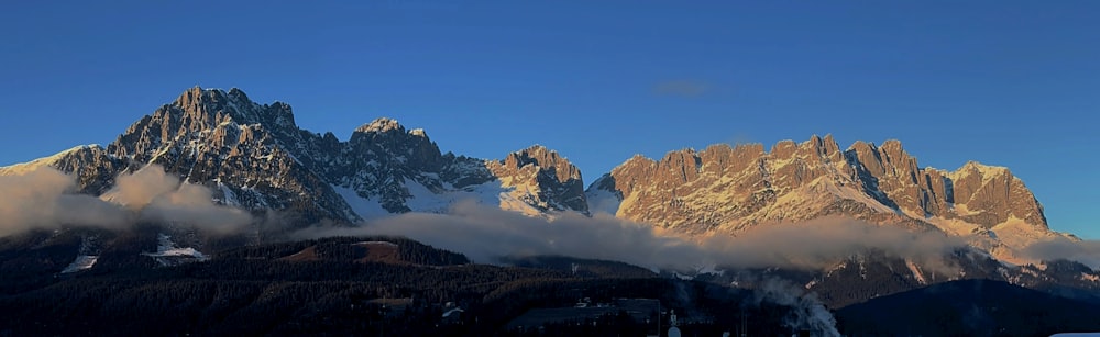 eine Gruppe von Bergen mit Wolken im Vordergrund