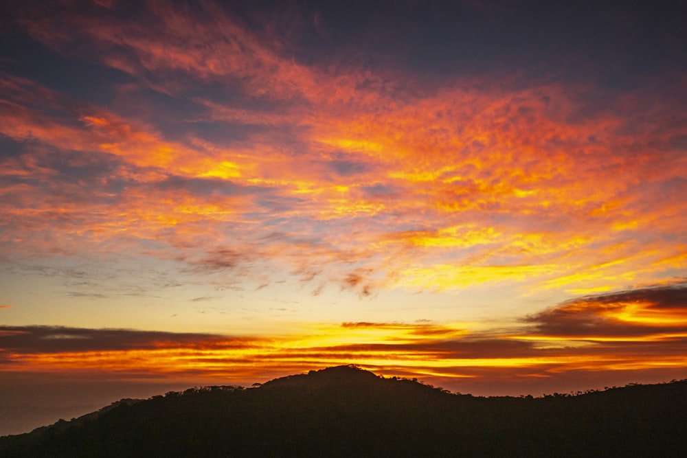 a sunset with a mountain in the background