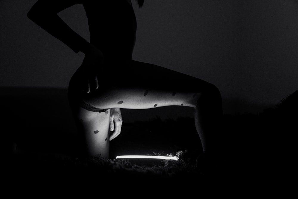 a woman standing in the dark with her legs crossed