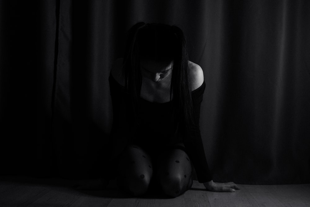 a woman sitting on the floor in a dark room