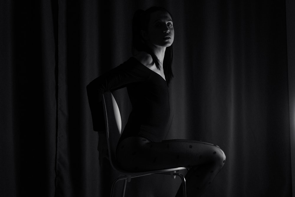 a woman sitting on a chair in a dark room