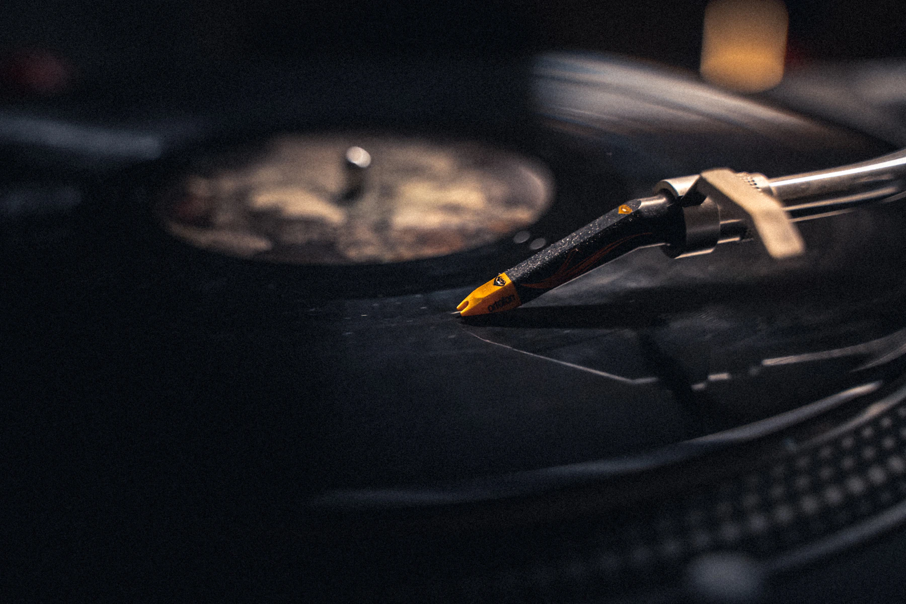 A turntable stylus resting in the groove of a black record