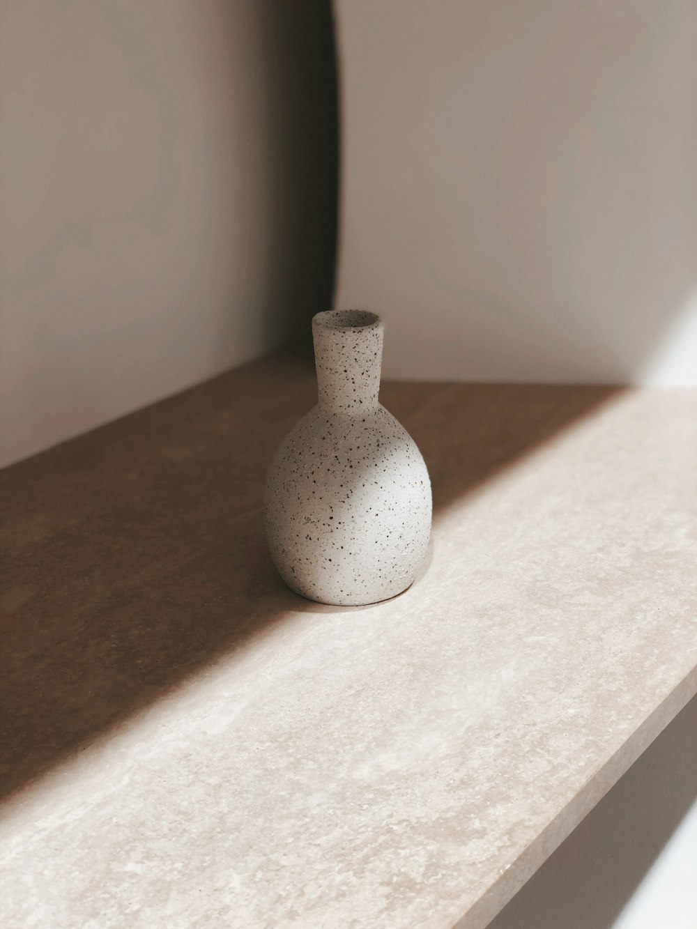 a white vase sitting on top of a shelf