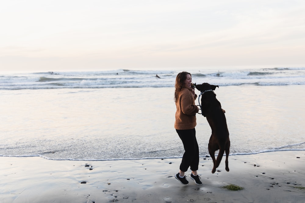 a woman standing on a beach with a dog