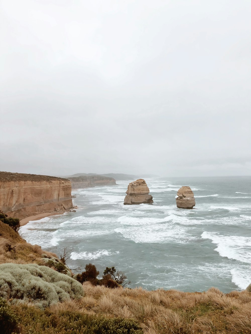 a view of the ocean with two large rocks in the distance