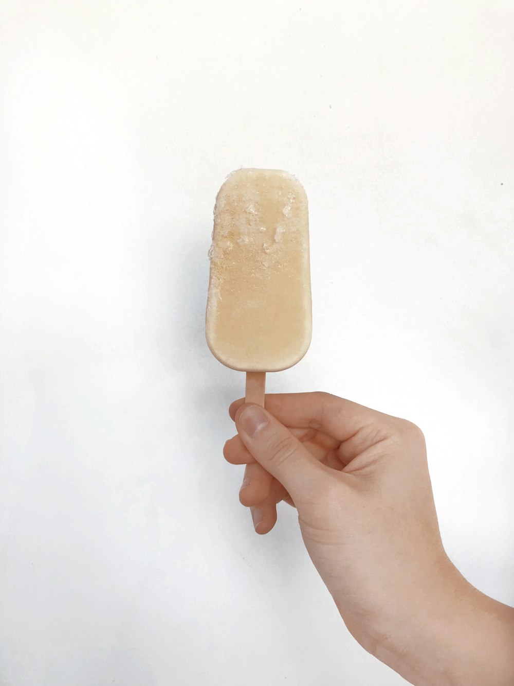 a hand holding a popsicle on a white background