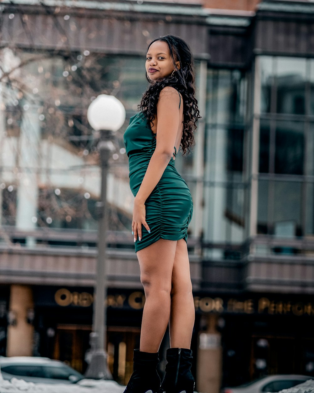 a woman in a green dress standing on a sidewalk