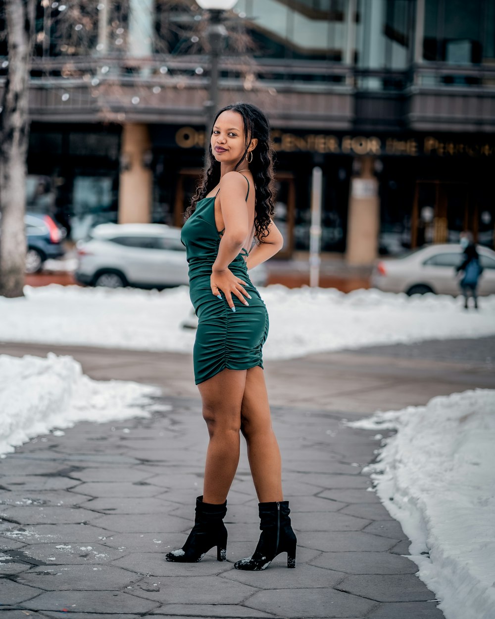 a woman in a green dress standing on a sidewalk