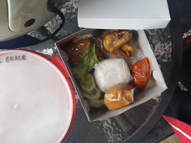 A takeout box filled with hot, flavorful chicken and sides packed to go.