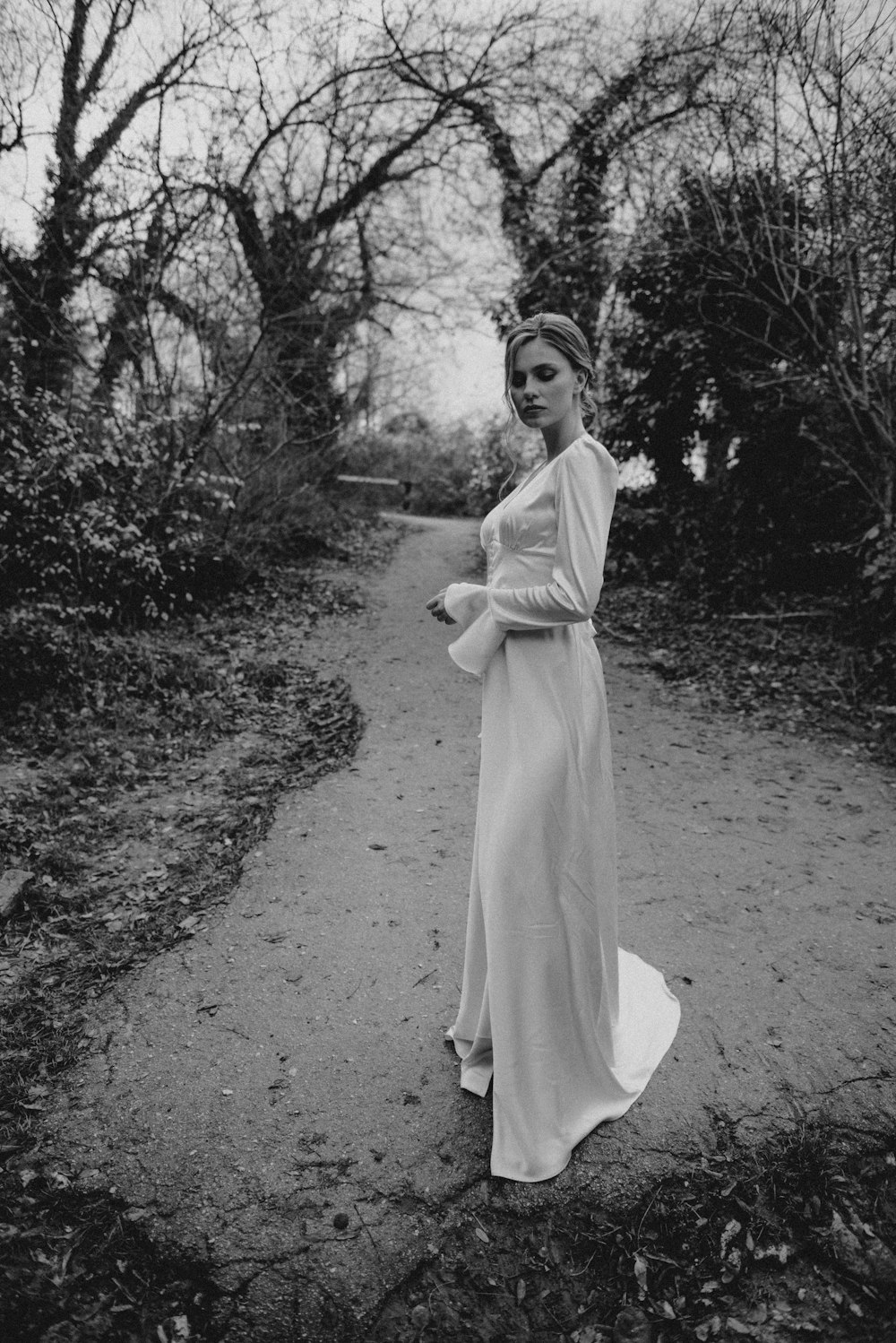 a woman in a long dress standing on a path