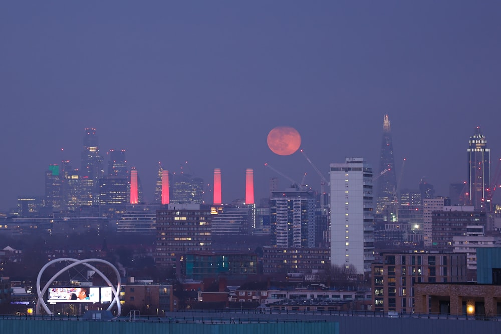 a view of a city at night with the moon in the sky