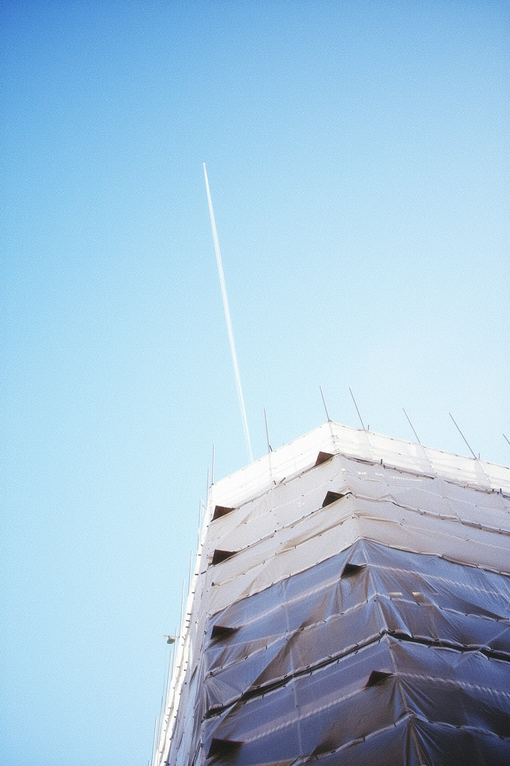 an airplane flying over a building under a blue sky