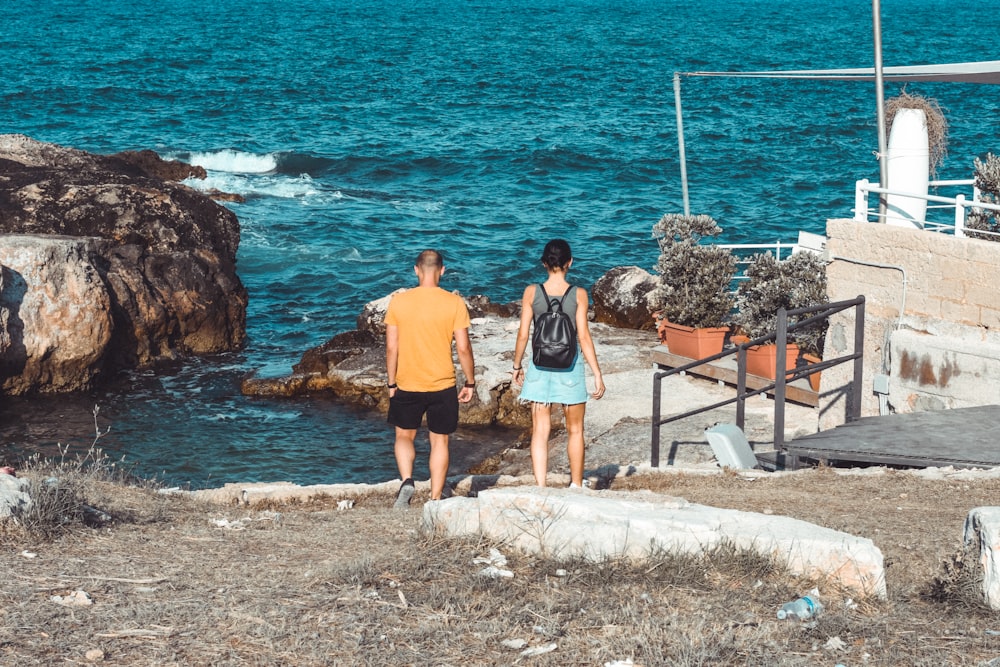 a man and a woman walking towards the ocean