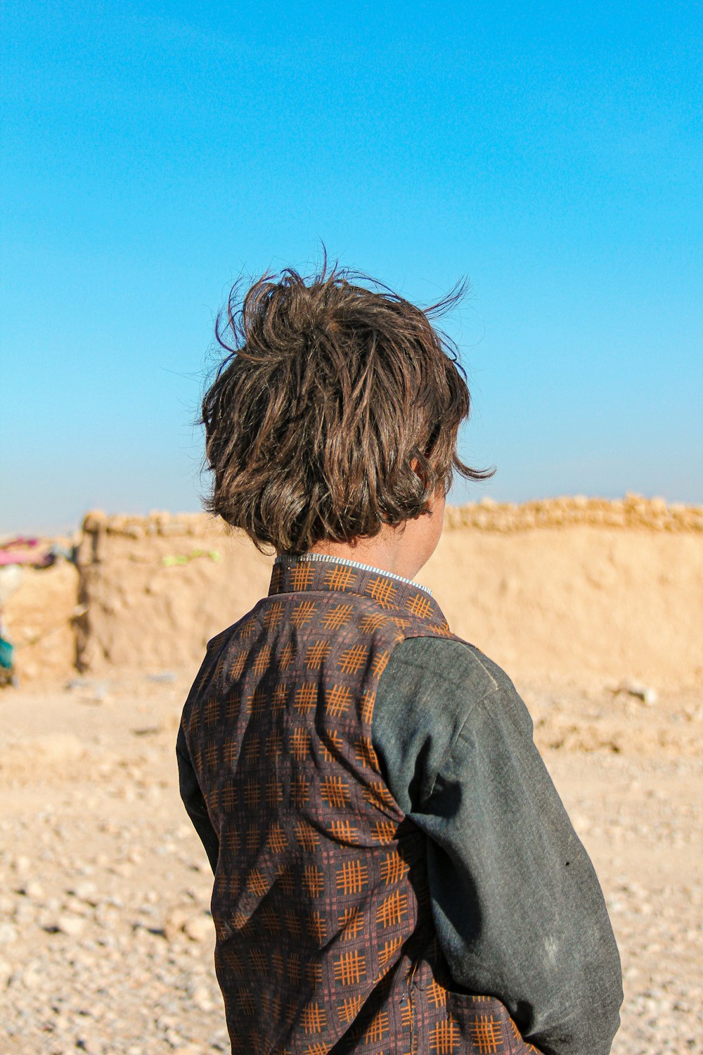 a young boy riding a skateboard across a sandy beach