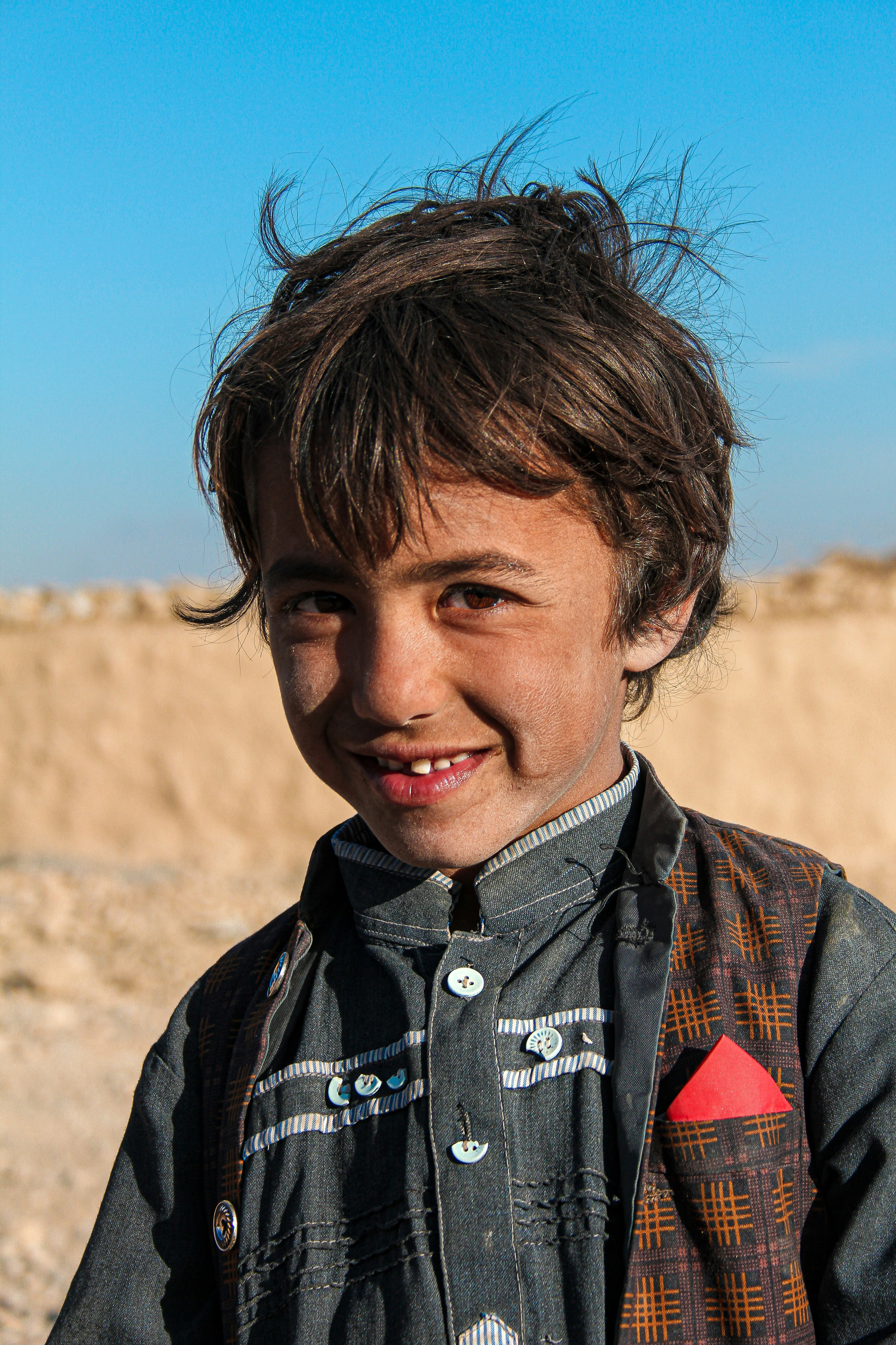 a young boy standing in front of a dirt hill