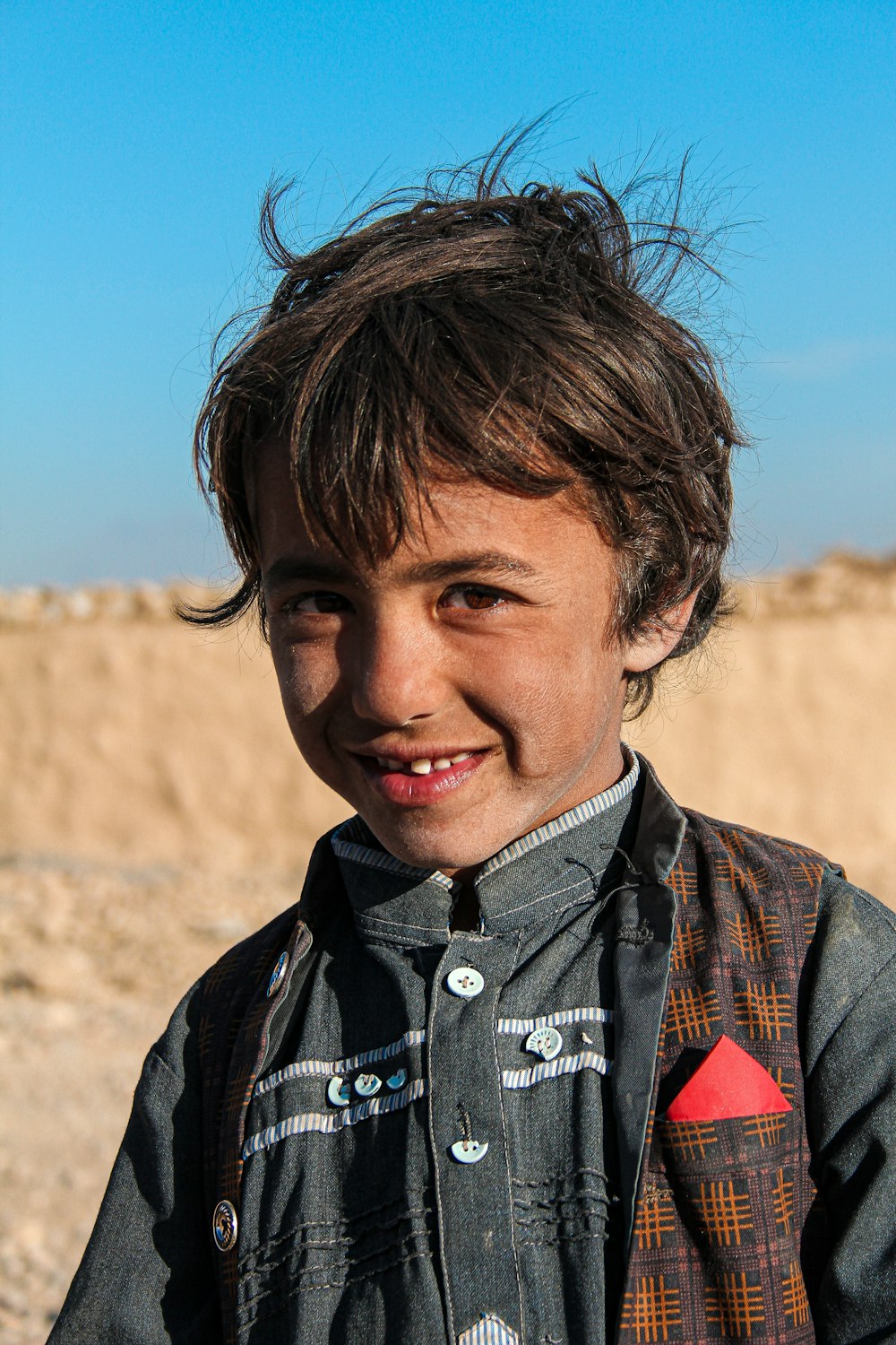 a young boy standing in front of a dirt hill