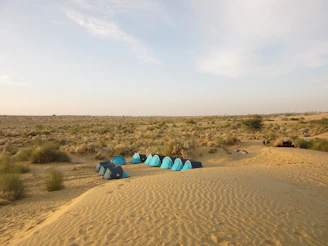 a group of blue tents sitting in the middle of a desert