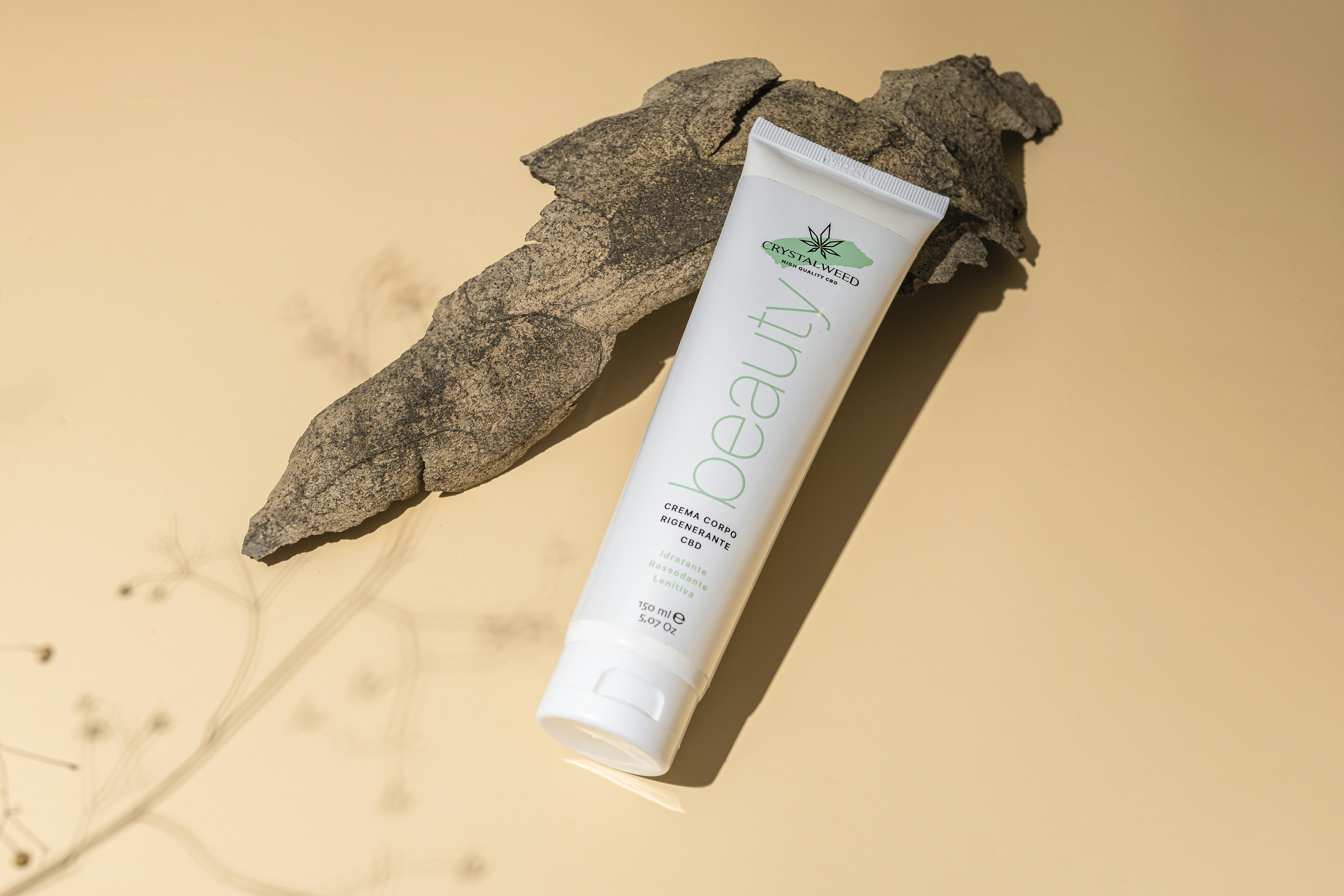 a tube of toothpaste sitting next to a leaf