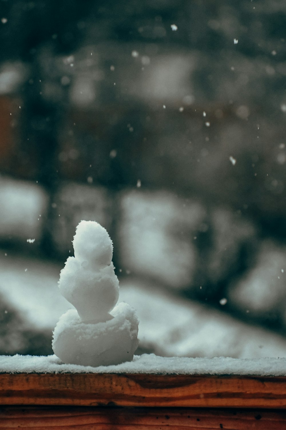 a small snowman sitting on top of a window sill