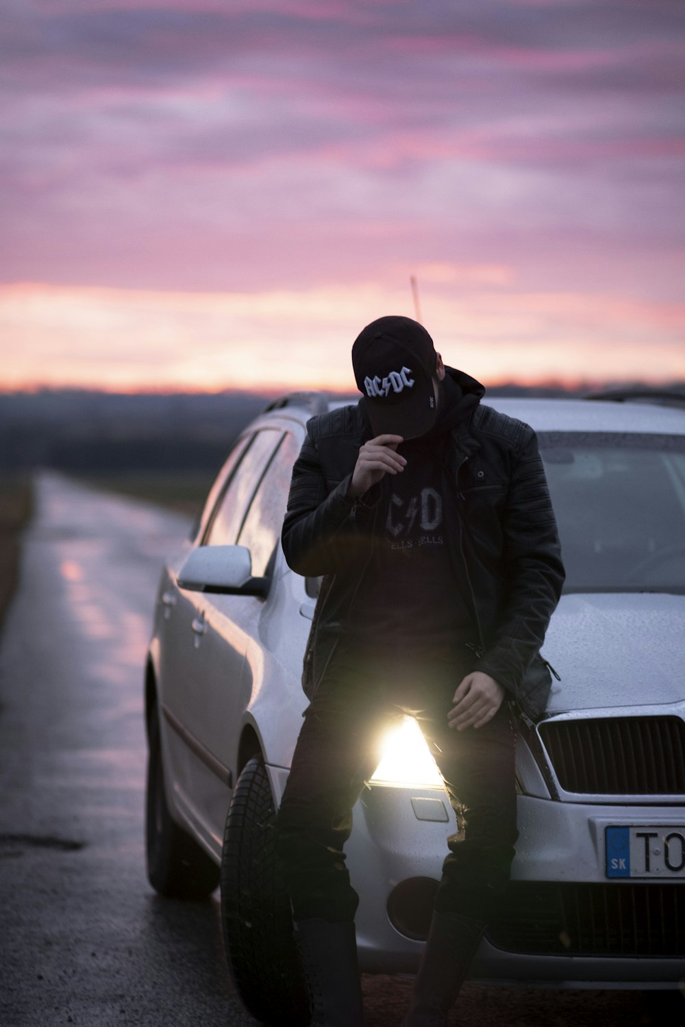 um homem sentado no capô de um carro